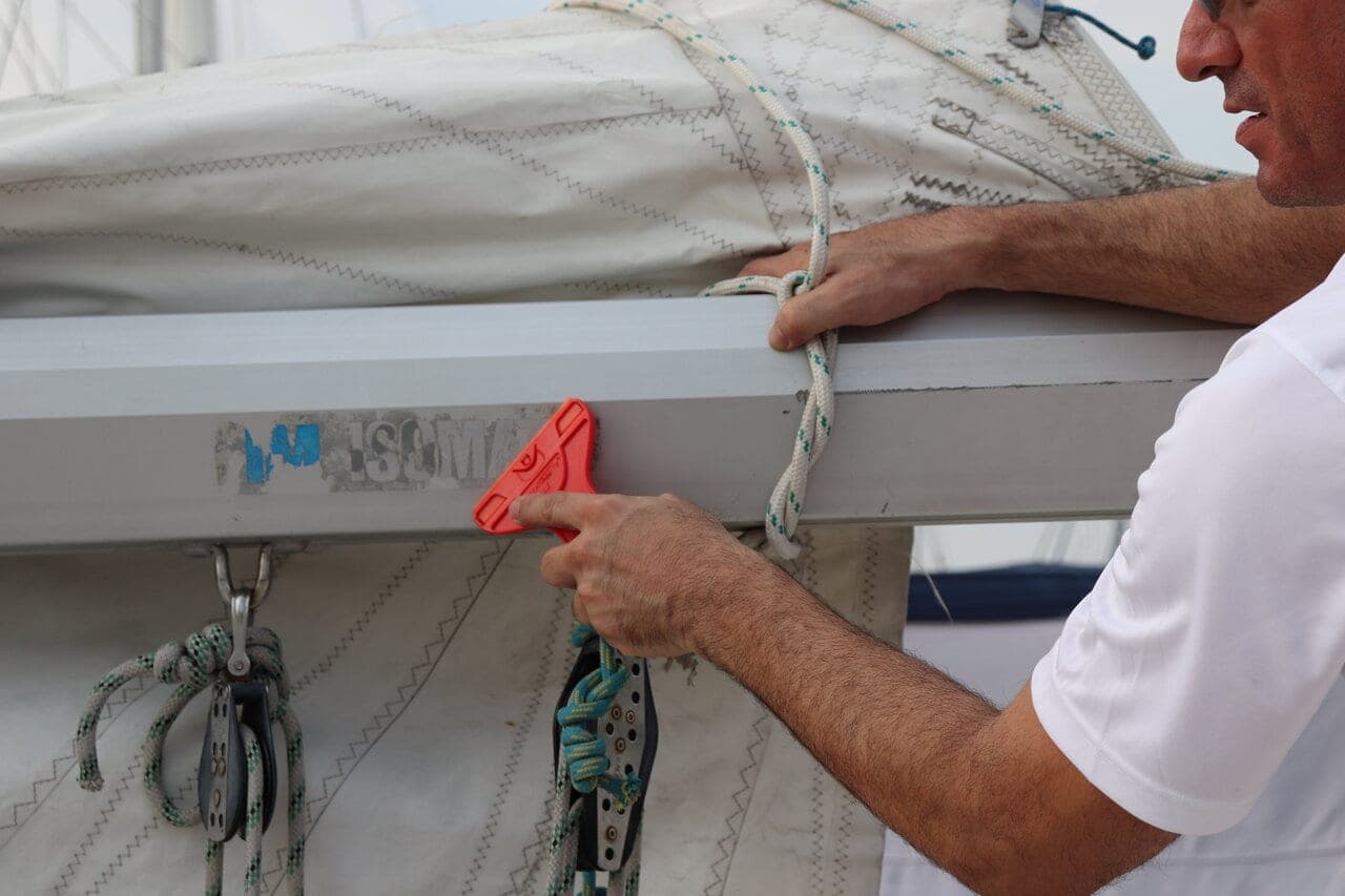 Person using a red non-scratch blade to clean or maintain a boat surface