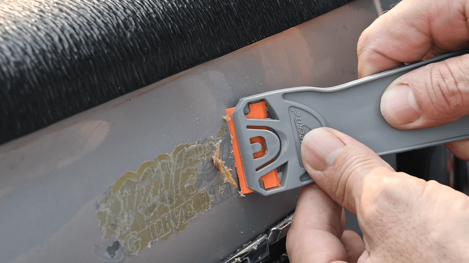 Person using Scraperite razor scraper to remove sticker residue from a surface